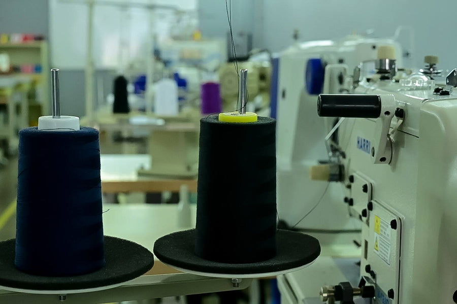 Navy and black thread cones on an industrial sewing machine at the HomeLand factory